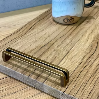 Detail von Holzmaserung, Kante und Messinggriff des Tabletts